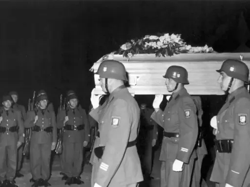 Militärische Ehreneskorte trägt einen mit Blumen geschmückten Sarg.