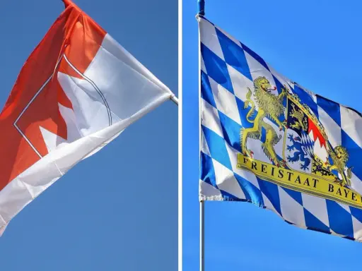 Zwei Fahnen im Wind: eine mit einem roten Ahornblatt, die andere mit dem Wappen des Freistaats Bayern, der stolz seine fränkischen Wurzeln zeigt.