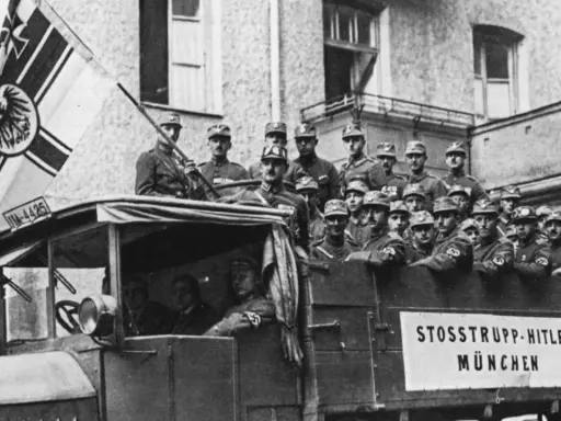 Männer in Uniformen, die an den Hitler-Putsch erinnern, stehen auf einem Lastwagen mit einer Fahne.
