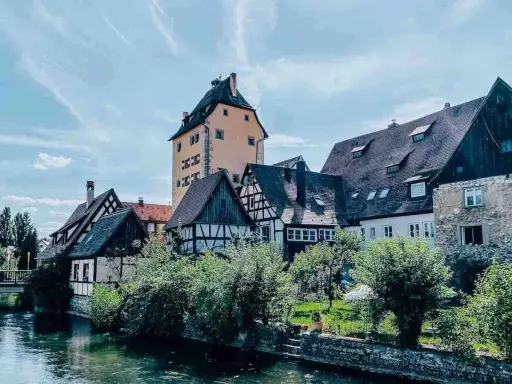 Fachwerkhäuser und ein hoher Turm am Flussufer in Hersbruck, Bayern.