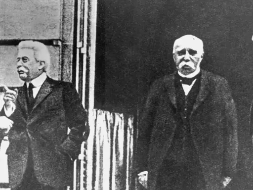 Vier Männer in Anzügen, die über den Friedensvertrag von Versailles diskutieren.