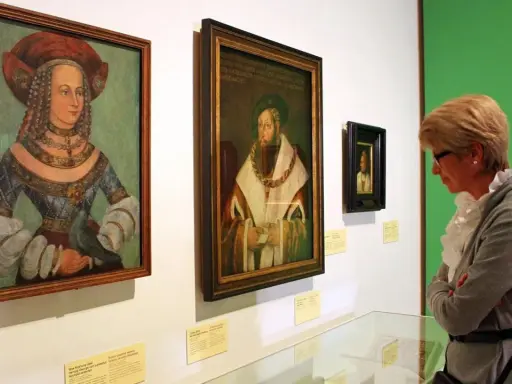 Eine Frau betrachtet Porträts der Familie Wittelsbach im Museum.