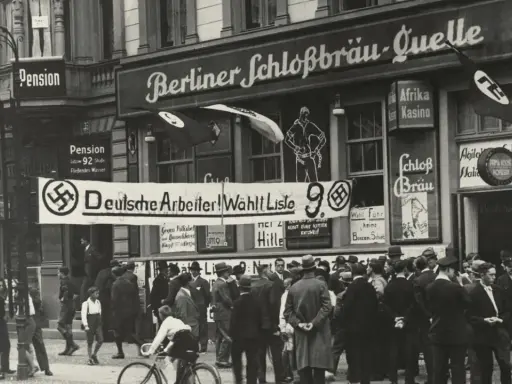 Menschenmenge vor einem Gebäude mit der Aufschrift "Berliner Schloßbräu-Quelle". Ein Banner verkündet "Deutsche Arbeiter! Wählt Liste 9". Hakenkreuzfahnen sind sichtbar, was auf die Zeit vor dem NSDAP Verbot hinweist.