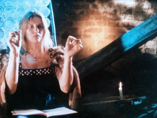 Annamirl Bierbichler in dunklem Kleid mit Pelzmantel, die Hände erhoben, im Schein einer Kerze.