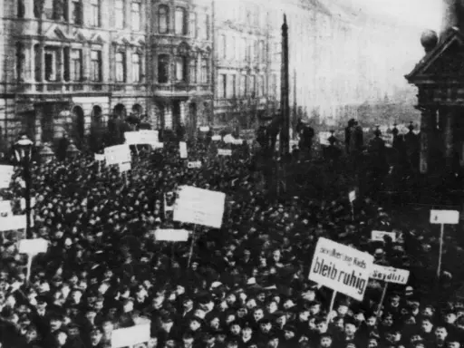 Massen demonstrieren in der Revolution 1918. Schilder mit Aufschriften wie "Seydlitz" und "Bleib ruhig" werden hochgehalten.