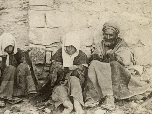 Drei Menschen, die an Lepra im Mittelalter leiden, sitzen vor einer Steinmauer. Ihre Kleidung ist zerlumpt, ihre Gesichter von der Krankheit gezeichnet.