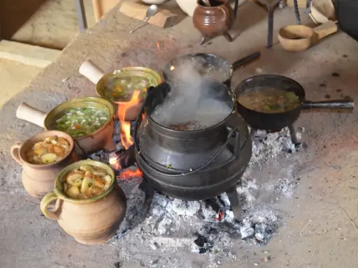 Ein mittelalterliches Festmahl: Eintöpfe und Suppen köcheln über offenem Feuer. Essen und trinken im Mittelalter war oft eine Gemeinschaftsangelegenheit.