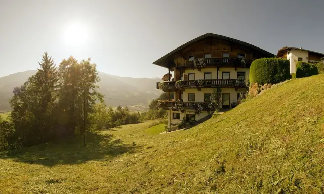 Sonnenbeschienene Alpenlandschaft mit einem traditionellen Haus, das an die Familie Schwarzenberg erinnert.