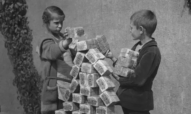 Kinder stapeln Bündel von Geldscheinen, ein Symbol für die Hyperinflation in Deutschland 1923.