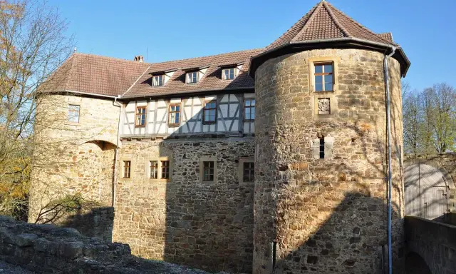 Die Burg von Bibra, ein historisches Gemäuer mit Rundturm und Fachwerk, strahlt im Sonnenlicht.