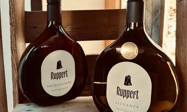Zwei Flaschen Ruppert Wein, Spätburgunder und Silvaner, stehen in einer Holzkiste. Ein Zeichen für den Weinbau Franken.