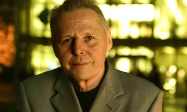 Porträt von Ulrich Enzensberger im Anzug, mit unscharfem, gelb beleuchtetem Hintergrund.