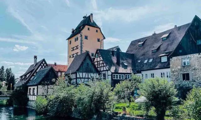 Fachwerkhäuser und ein hoher Turm am Flussufer in Hersbruck, Bayern.