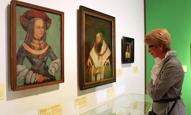 Eine Frau betrachtet Porträts der Familie Wittelsbach im Museum.