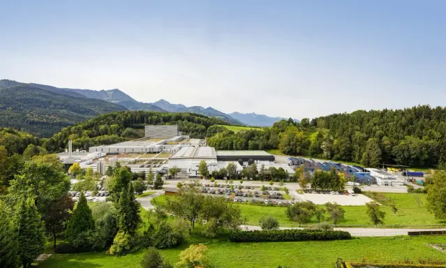 Großer Industriebetrieb in Bad Adelholzen, eingebettet in grüne Hügel und Berge.