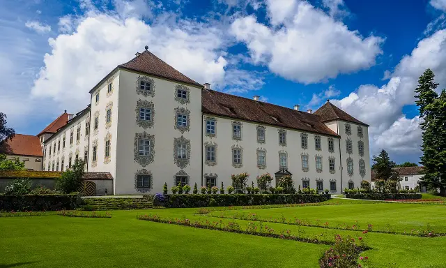 Schloss Waldburg-Zeil mit gepflegtem Garten und blauem Himmel mit Wolken.