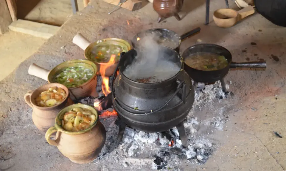 Ein mittelalterliches Festmahl: Eintöpfe und Suppen köcheln über offenem Feuer. Essen und trinken im Mittelalter war oft eine Gemeinschaftsangelegenheit.