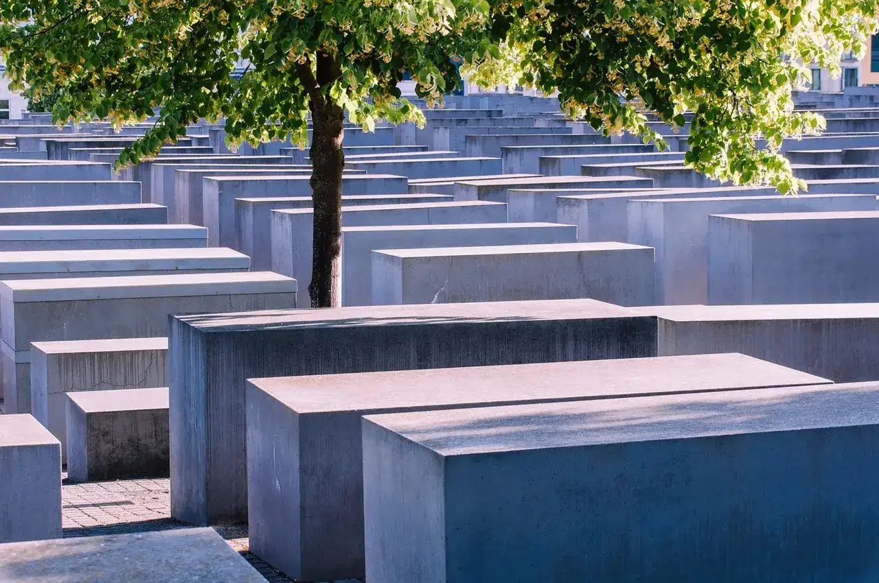 Gedenkst&auml;tte f&uuml;r die ermordeten Juden Europas. Betonstelen erinnern an das NS-Verbrechen. Ein Baum spendet Schatten.