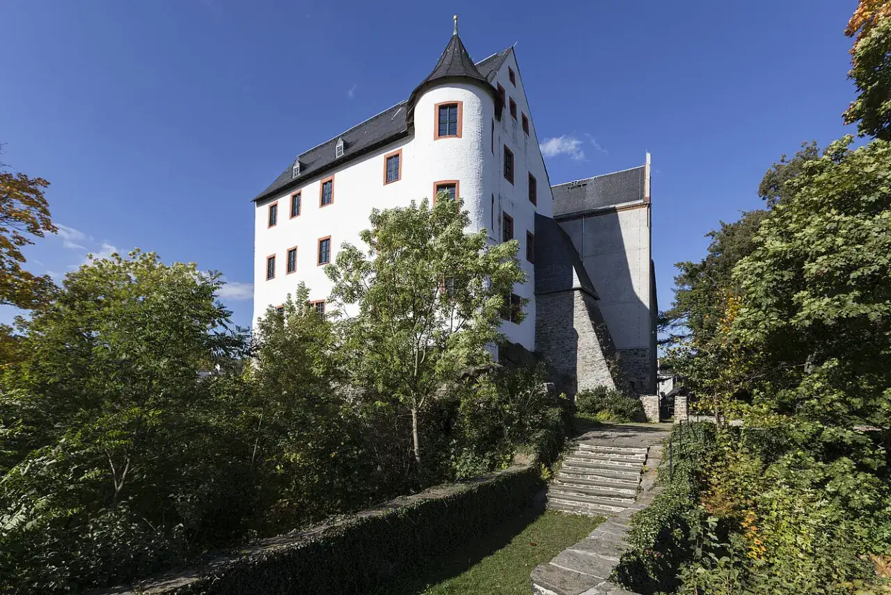 Schwarzenberg Familie: Weißes Schloss mit Turm, umgeben von Bäumen und einer Steintreppe.