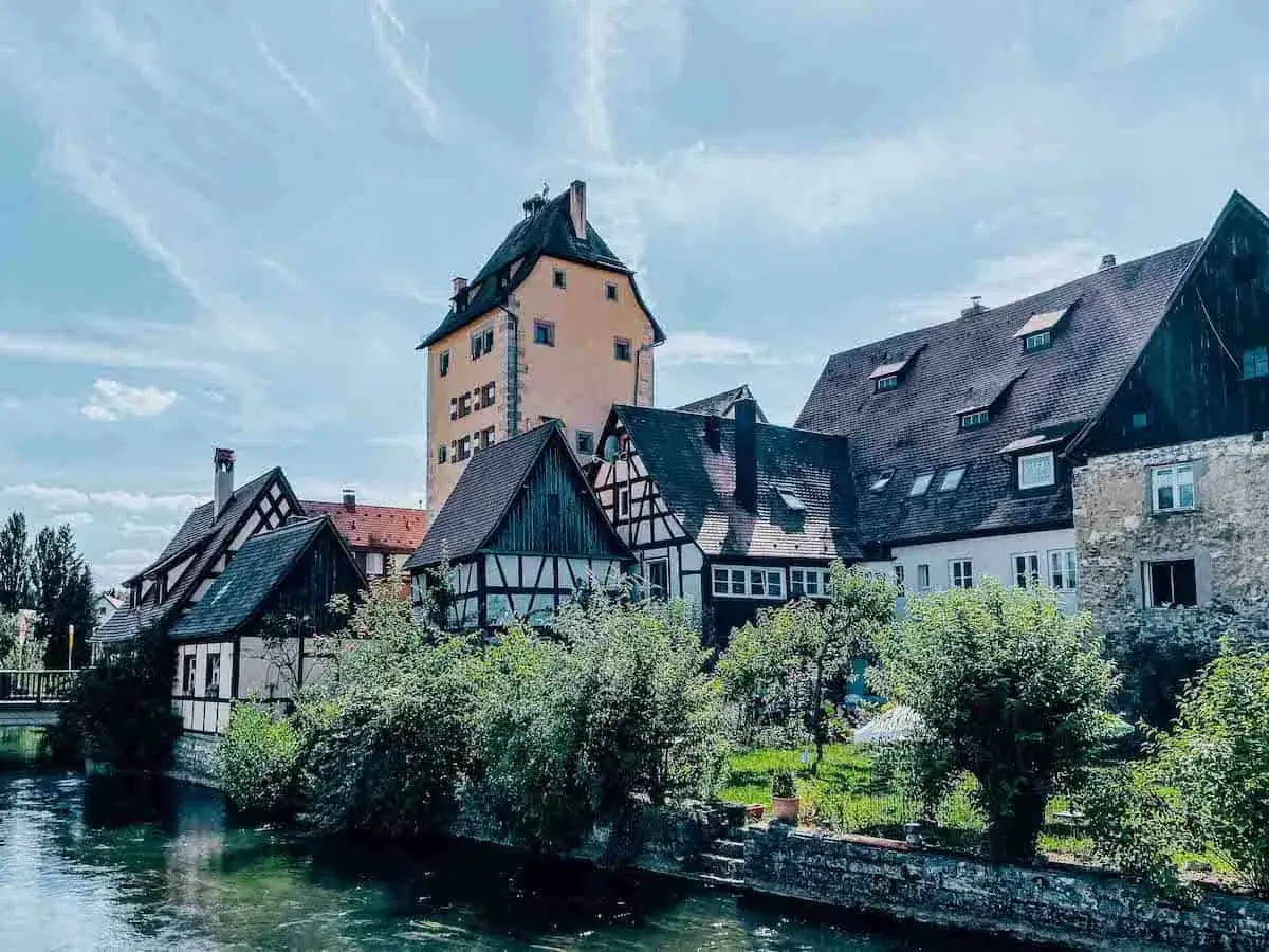 Fachwerkh&auml;user und ein hoher Turm s&auml;umen einen Fluss in Hersbruck, Bayern.