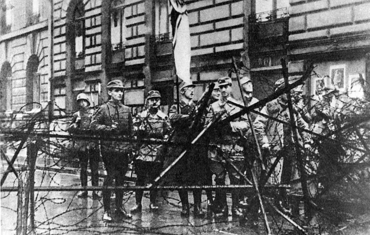 Soldaten sichern ein Geb&auml;ude mit Stacheldraht. Die Szene erinnert an den Putschversuch Hitlers.