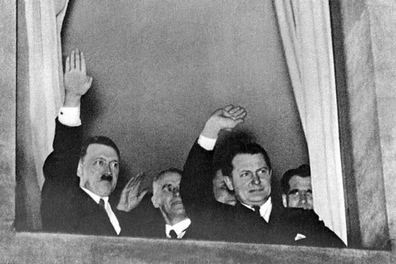 Am 30. Januar 1933 grüßen Hitler und andere Männer vom Fenster aus.