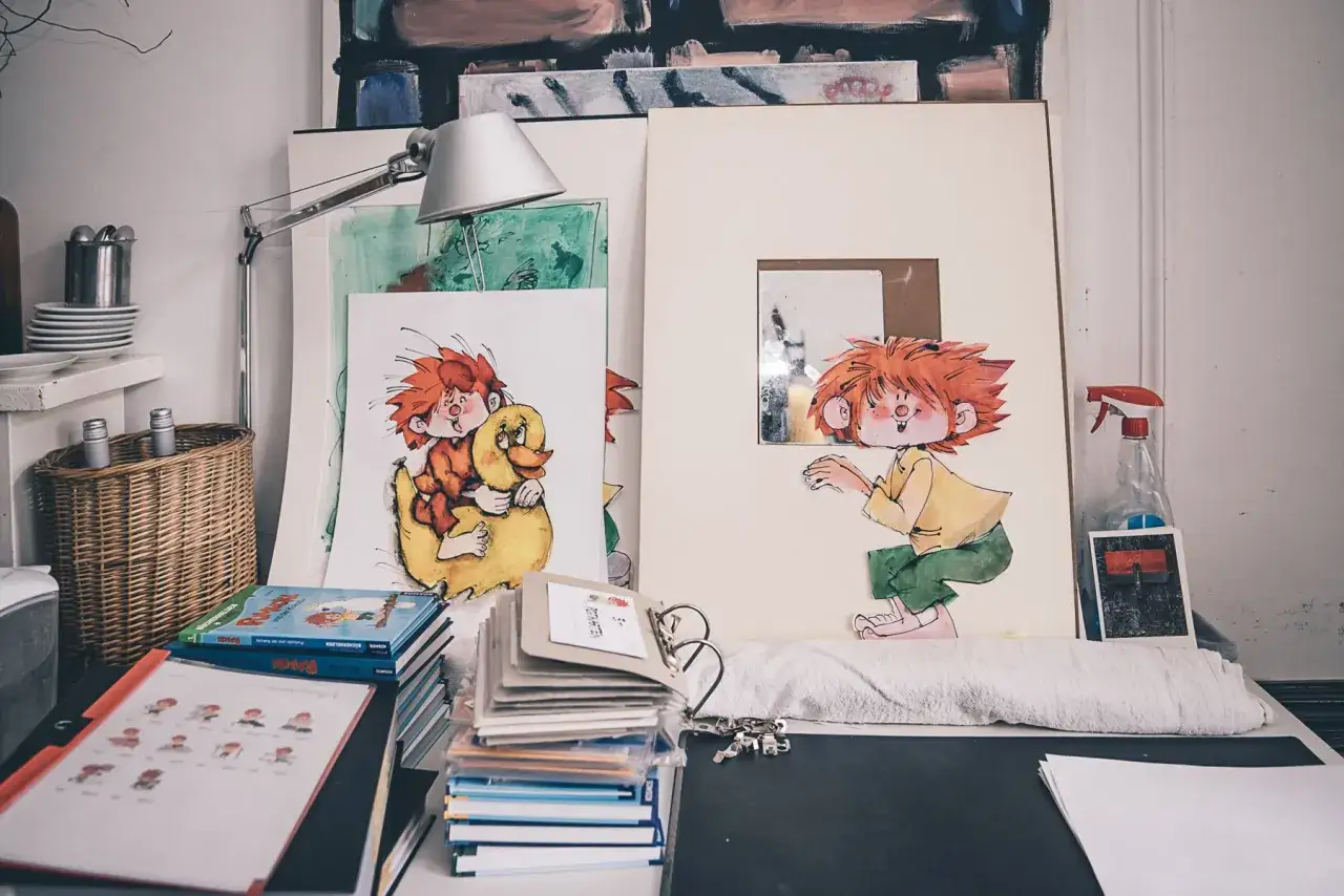 Der kleine Kobold Pumuckl, alt und lieb, sitzt auf einem gelben Enten-Schwimmring. Daneben eine weitere Zeichnung von ihm.