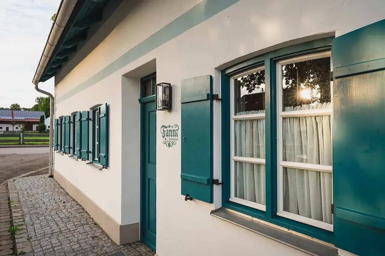 Ein Haus mit gr&uuml;nen Fensterl&auml;den und einem Schild 
