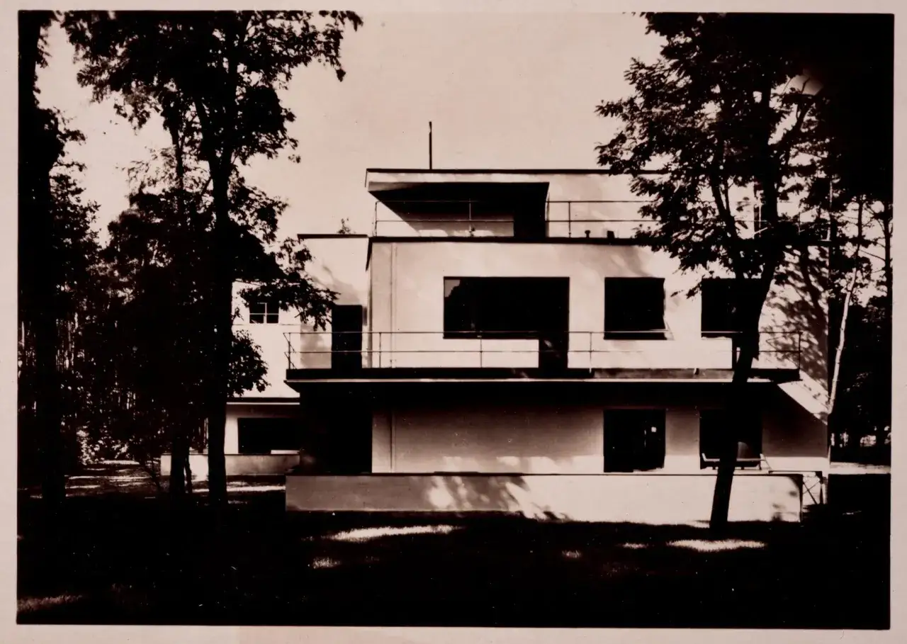 Kubistische Architektur der 1920er Jahre: Ein helles, modernes Haus mit klaren Linien und großen Fenstern, umgeben von Bäumen.