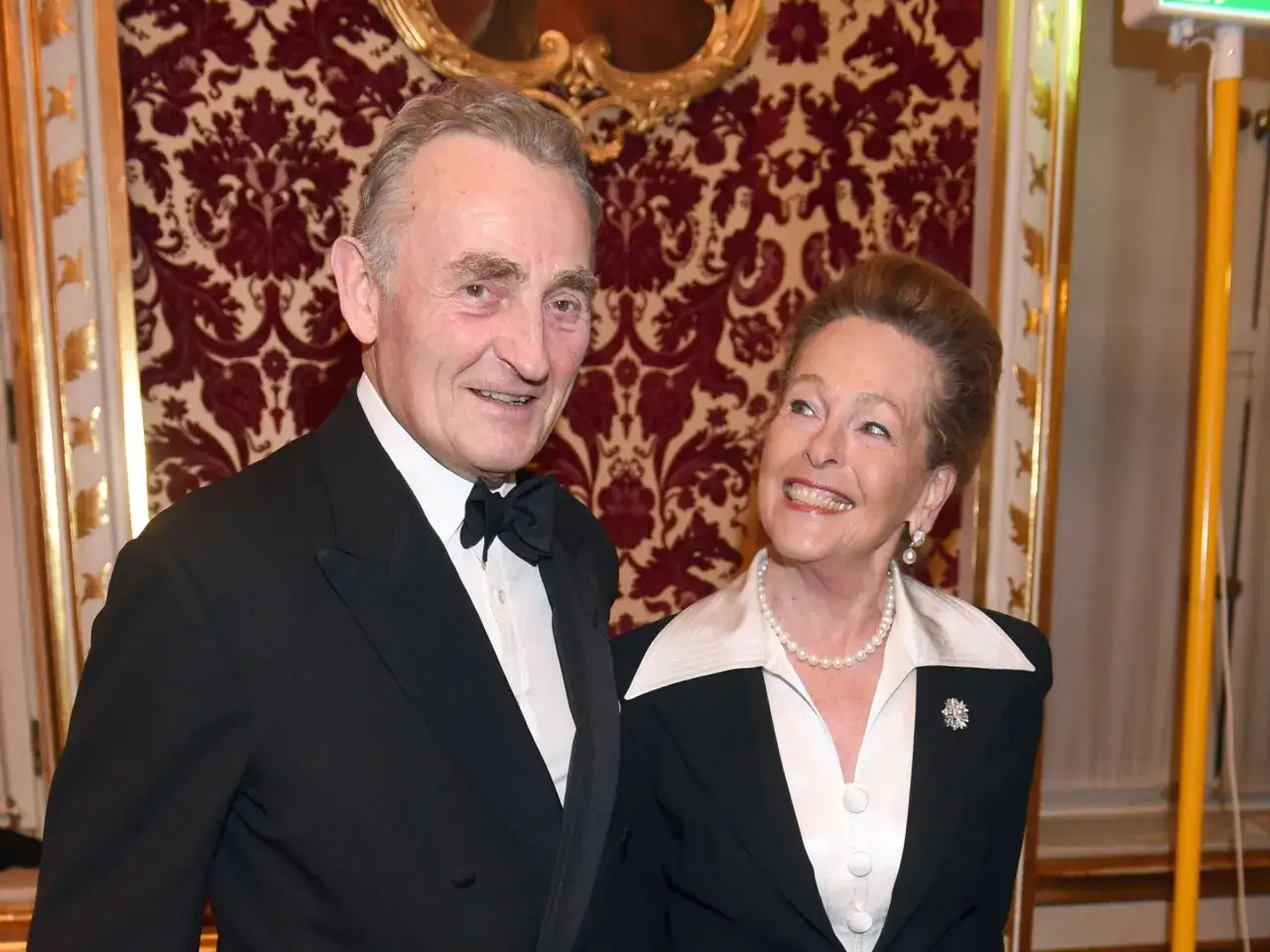 Max Emanuel Herzog in Bayern, elegant gekleidet, lächelt neben einer Dame mit Perlenkette.