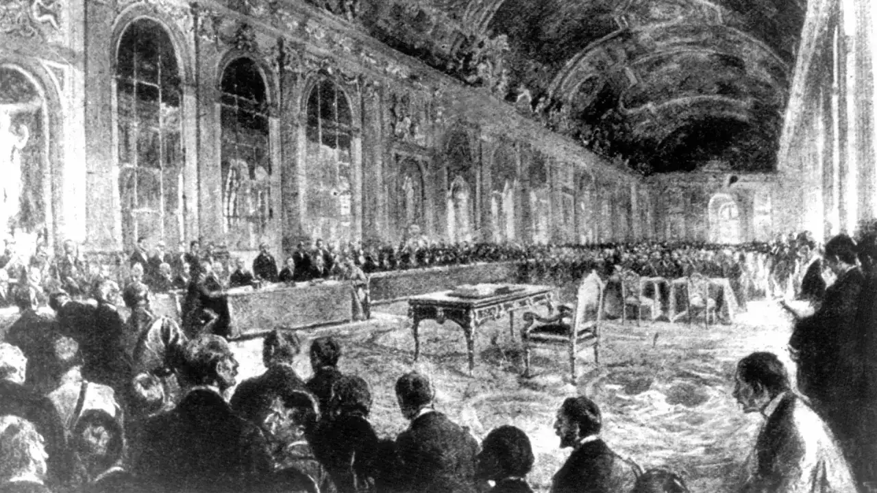Gro&szlig;er Saal mit vielen Menschen, die sich versammelt haben. Ein Tisch mit Stuhl steht im Vordergrund. Dies ist eine Darstellung des Friedensvertrags von Versailles.
