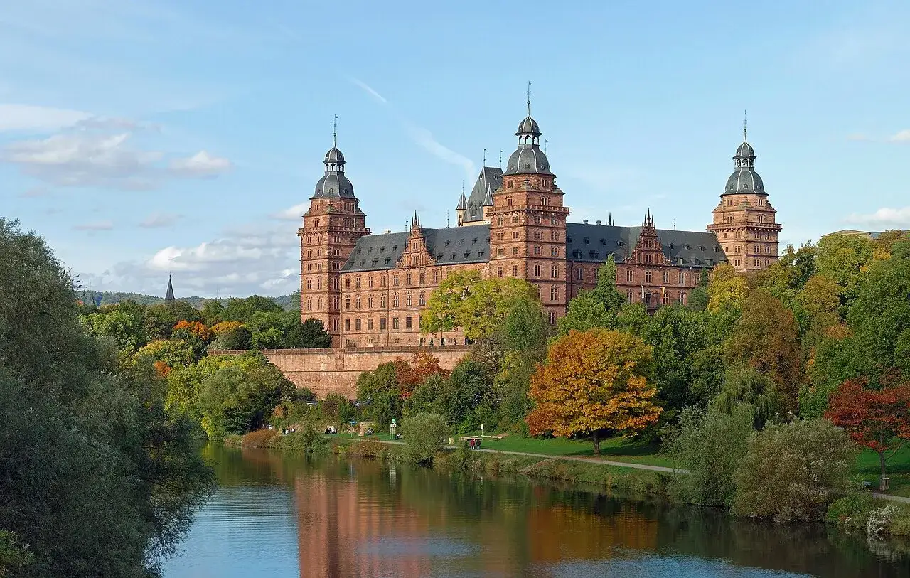 Schloss Johannisberg, ein pr&auml;chtiges Bauwerk, spiegelt sich im Wasser. Die Herbstfarben der B&auml;ume um das Schloss von Bibra sind leuchtend.