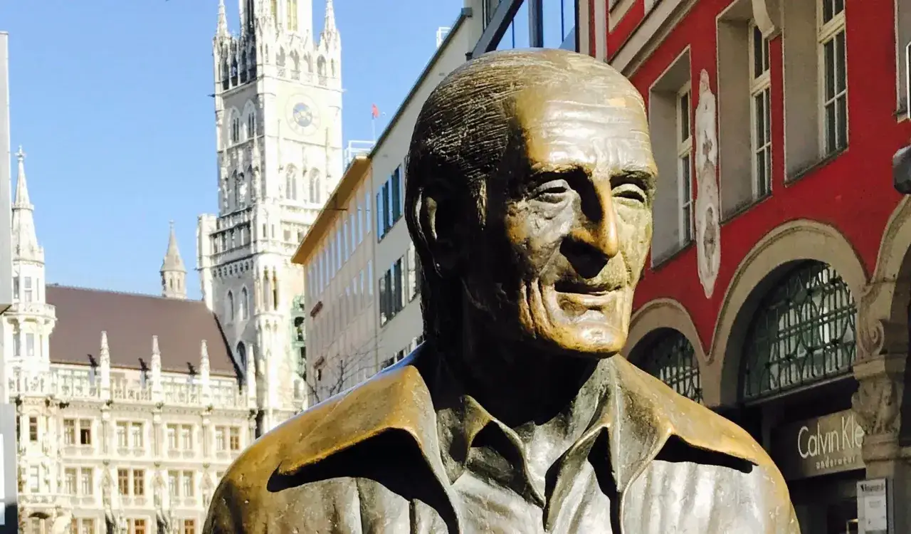 Bronzestatue von Sigi Sommer in M&uuml;nchen, mit dem Neuen Rathaus im Hintergrund.