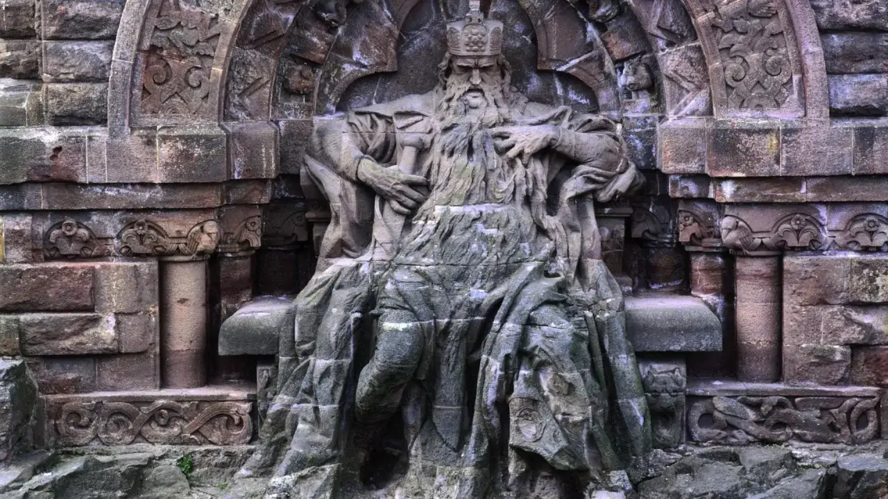 Monumentale Steinskulptur von Friedrich I. Barbarossa mit Bart und Krone, der auf einem Thron sitzt.