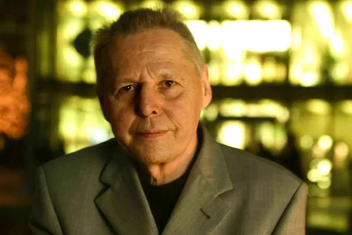 Porträt von Ulrich Enzensberger im grauen Anzug, der Blick nach vorne gerichtet, im Hintergrund unscharfes gelbes Licht.
