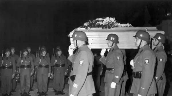 Militärische Ehreneskorte trägt einen mit Blumen geschmückten Sarg.