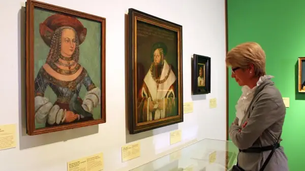 Eine Frau betrachtet Porträts der Familie Wittelsbach im Museum.