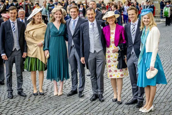 Gruppe von Personen in festlicher Kleidung, darunter Frauen in Kleidern und Männer in Anzügen.