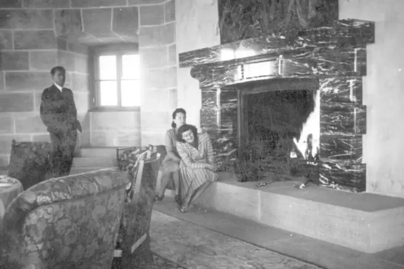 Zwei Frauen entspannen sich 1944 am Kamin im Kehlsteinhaus. Ein Mann steht im Hintergrund.