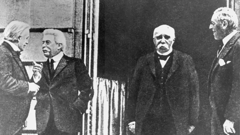 Vier Männer in Anzügen, die über den Friedensvertrag von Versailles diskutieren.